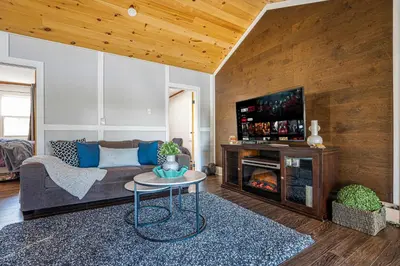a living room with a couch and a tv at Rustic Lakefront Cottage with Fire Pit & Scenic Views in Brechin