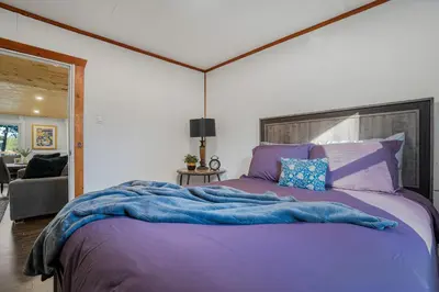 a bedroom with a large bed with purple sheets at Rustic Lakefront Cottage with Fire Pit & Scenic Views in Brechin