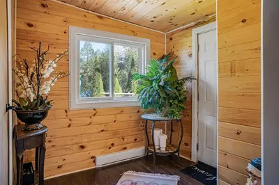 a room with wooden walls and a window and plants at Rustic Lakefront Cottage with Fire Pit & Scenic Views in Brechin