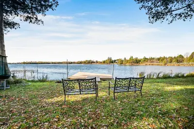 a table and two chairs in front of a lake at Rustic Lakefront Cottage with Fire Pit & Scenic Views in Brechin