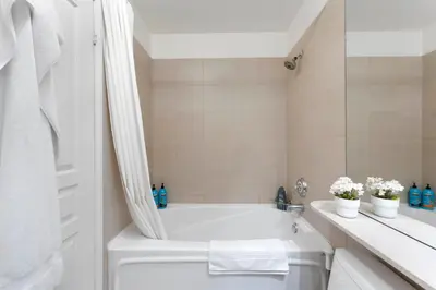 a white bathroom with a tub and a toilet at Luxury 1-Bedroom Condo in Yorkville, Downtown Toronto in Toronto