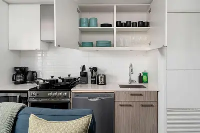 a kitchen with white cabinets and a stove top oven at Chic 2BR Condo Toronto Core Steps to Eaton Centre in Toronto