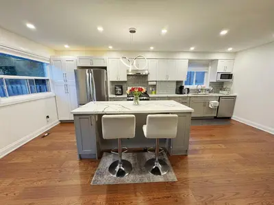 a kitchen with white cabinets and a island with two chairs at Quite room finch birchmunt in Toronto