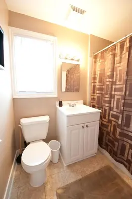 a bathroom with a toilet and a sink and a window at Misty Retreat in Niagara Falls