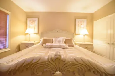 a bedroom with a large white bed with two lamps at STONEHAVEN RETREAT in Niagara Falls