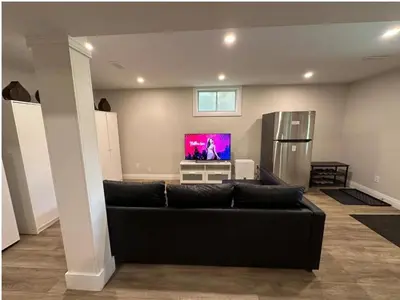 a living room with a black couch and a tv at 1-Bedroom 1Bathroom Entire Unit closer to Fairview Mall & Waterloo Airport in Kitchener