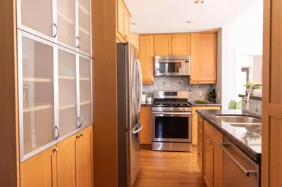 a kitchen with wooden cabinets and stainless steel appliances at New York Style Brownstone Elegant Home in Toronto's Vibrant King West in Toronto