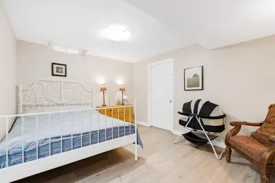 a white bedroom with a bed and a chair at Cozy Private Basement Suite Beside Plaza Free Parking Walk to Groceries & Dining in Richmond Hill