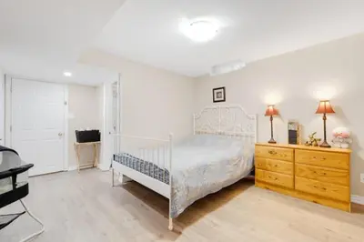 a bedroom with a white bed and a wooden dresser at Cozy Private Basement Suite Beside Plaza Free Parking Walk to Groceries & Dining in Richmond Hill