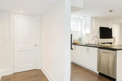 a kitchen with white cabinets and a white door at Bright 2 Bed Basement Near Square One Mall Family Friendly Stay in Mississauga