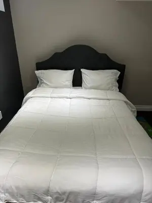 a large bed with white sheets and pillows at Cozy and comfy 2 Bed rooms in Mississauga