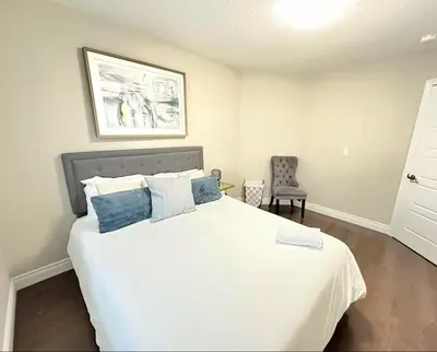 a bedroom with a white bed and a chair at Fieldstone Estate in Tillsonburg