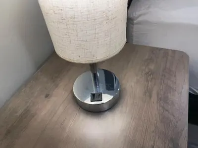 a lamp sitting on a wooden table next to a bed at Bright & Cozy Basement Retreat in Oshawa