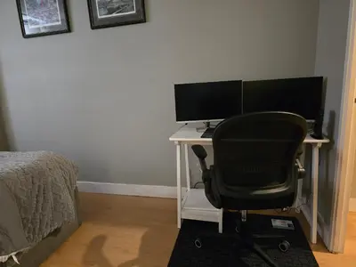 a desk with two monitors and a chair in a bedroom at Simple entire apartment 2 bedroom night rest in Kitchener
