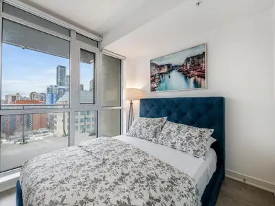 a bedroom with a bed and a large window at VOGUE Suites Toronto Downtown - Entertainment District in Toronto
