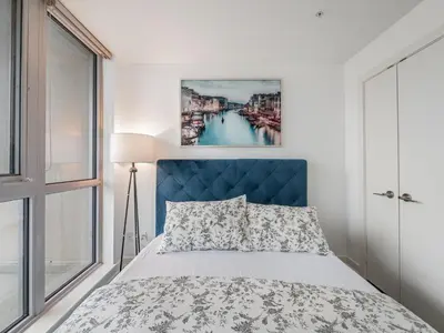 a bedroom with a bed with a blue headboard at VOGUE Suites Toronto Downtown - Entertainment District in Toronto