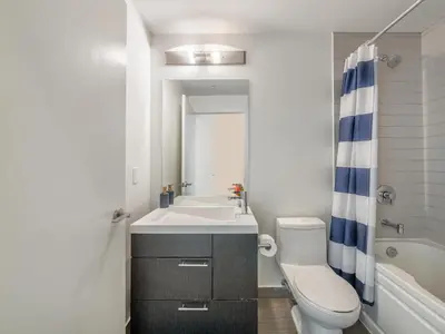 a bathroom with a sink and a toilet and a tub at VOGUE Suites Toronto Downtown - Entertainment District in Toronto