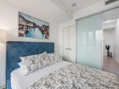 a bedroom with a bed with a blue headboard at VOGUE Suites Toronto Downtown - Entertainment District in Toronto