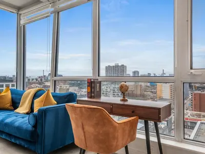 a living room with a blue couch and large windows at VOGUE Suites Toronto Downtown - Entertainment District in Toronto
