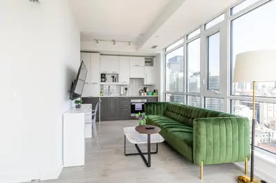 a living room with a green couch and a kitchen at VOGUE Suites Toronto Downtown - Entertainment District in Toronto