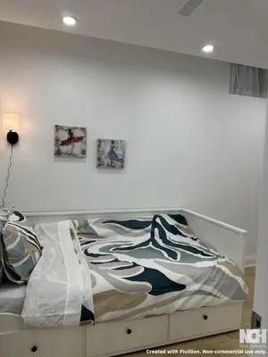 a bed in a bedroom with two pictures on the wall at Modern 2-Bedroom Apartment in Luxury Home with Gym in Richmond Hill