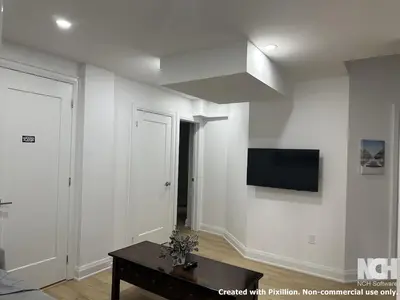 a living room with a tv on a white wall at Modern 2-Bedroom Apartment in Luxury Home with Gym in Richmond Hill