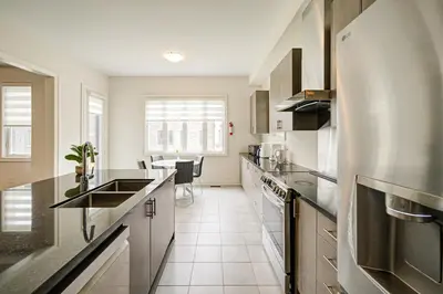 a kitchen with stainless steel appliances and a table at Modern Spacious Luxury detached-House new in RH in Richmond Hill