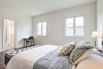 a bedroom with a large bed with two windows at Very Modern New Luxury House in RichmondHill in Richmond Hill