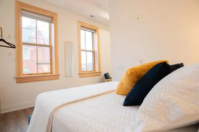 a bedroom with a white bed with two windows at Downtown Stratford - The Blowes Inn in Stratford
