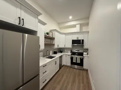 a kitchen with white cabinets and stainless steel appliances at Downtown Stratford - The Blowes Inn in Stratford