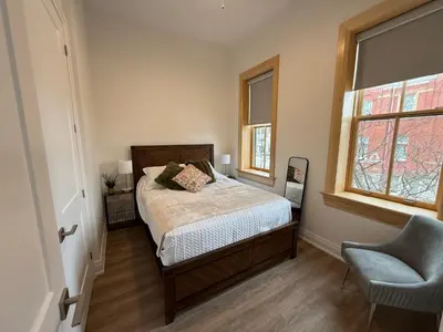 a bedroom with a bed and a chair and a window at Downtown Stratford - The Blowes Inn in Stratford