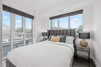 a white bedroom with a large bed and windows at Chic 2-Bedroom Apartment with Parking in Toronto