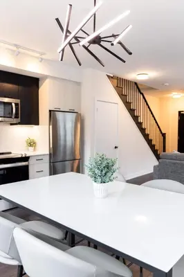 a kitchen and dining room with a white table and chairs at Chic 2-Bedroom Apartment with Parking in Toronto