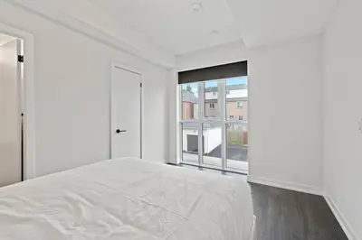 a white bedroom with a bed and a large window at Chic 2-Bedroom Apartment with Parking in Toronto