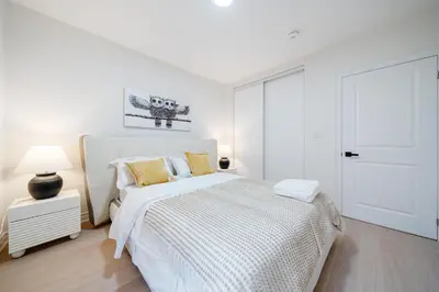 a white bedroom with a white bed with yellow pillows at Luxury Group Stay in King West in Toronto