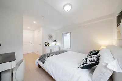 a white bedroom with a bed and a desk at Luxury Group Stay in King West in Toronto