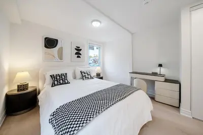 a white bedroom with a large bed and a desk at Luxury Group Stay in King West in Toronto