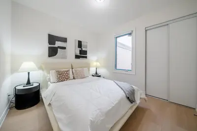 a white bedroom with a bed and a window at Luxury Group Stay in King West in Toronto