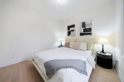 a white bedroom with a large bed and two lamps at Luxury Group Stay in King West in Toronto