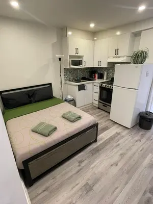 a bedroom with a bed and a kitchen with white cabinets at Exclusive Queen St Downtown Full House-PRIVATE PATIO in Toronto