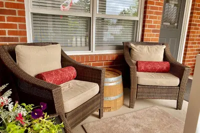 two wicker chairs and a barrel on a porch at Top 1% Quiet Private Guestroom 2ppl Old Town NOTL in Niagara on the Lake