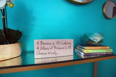 a shelf with books and a sign on a wall at The Coupe: A Hip Wine Lovers Retreat in NOTL! ✌️ in Niagara on the Lake