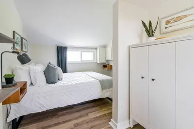 a white bedroom with a bed and a window at Top 5% Tiny Home by River/Lake in Old Town NOTL in Niagara on the Lake