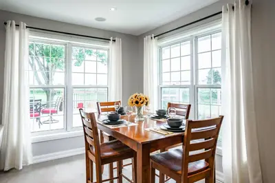 a dining room with a table and chairs and windows at Vineyard 2 Bed Farm Home | Mins to Town & Wineries in Niagara on the Lake