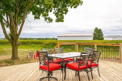 a table and chairs on a deck with a tree at Vineyard 2 Bed Farm Home | Mins to Town & Wineries in Niagara on the Lake
