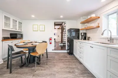 a kitchen with a table and a sink and a refrigerator at Central Historic Cottage 4ppl in Heart of NOTL in Niagara on the Lake