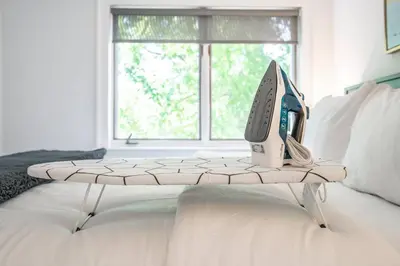 a table with a computer on top of a bed at Central Historic Cottage 4ppl in Heart of NOTL in Niagara on the Lake
