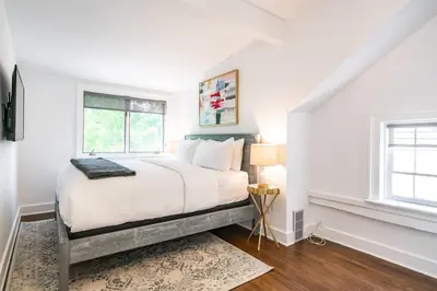 a white bedroom with a bed and two windows at Central Historic Cottage 4ppl in Heart of NOTL in Niagara on the Lake