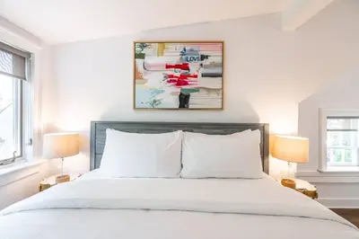 a bedroom with a white bed with two lamps at Central Historic Cottage 4ppl in Heart of NOTL in Niagara on the Lake