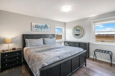 a bedroom with a large bed and two windows at Single Level Vineyard Home | 6 PPL | Pet Friendly in Niagara on the Lake